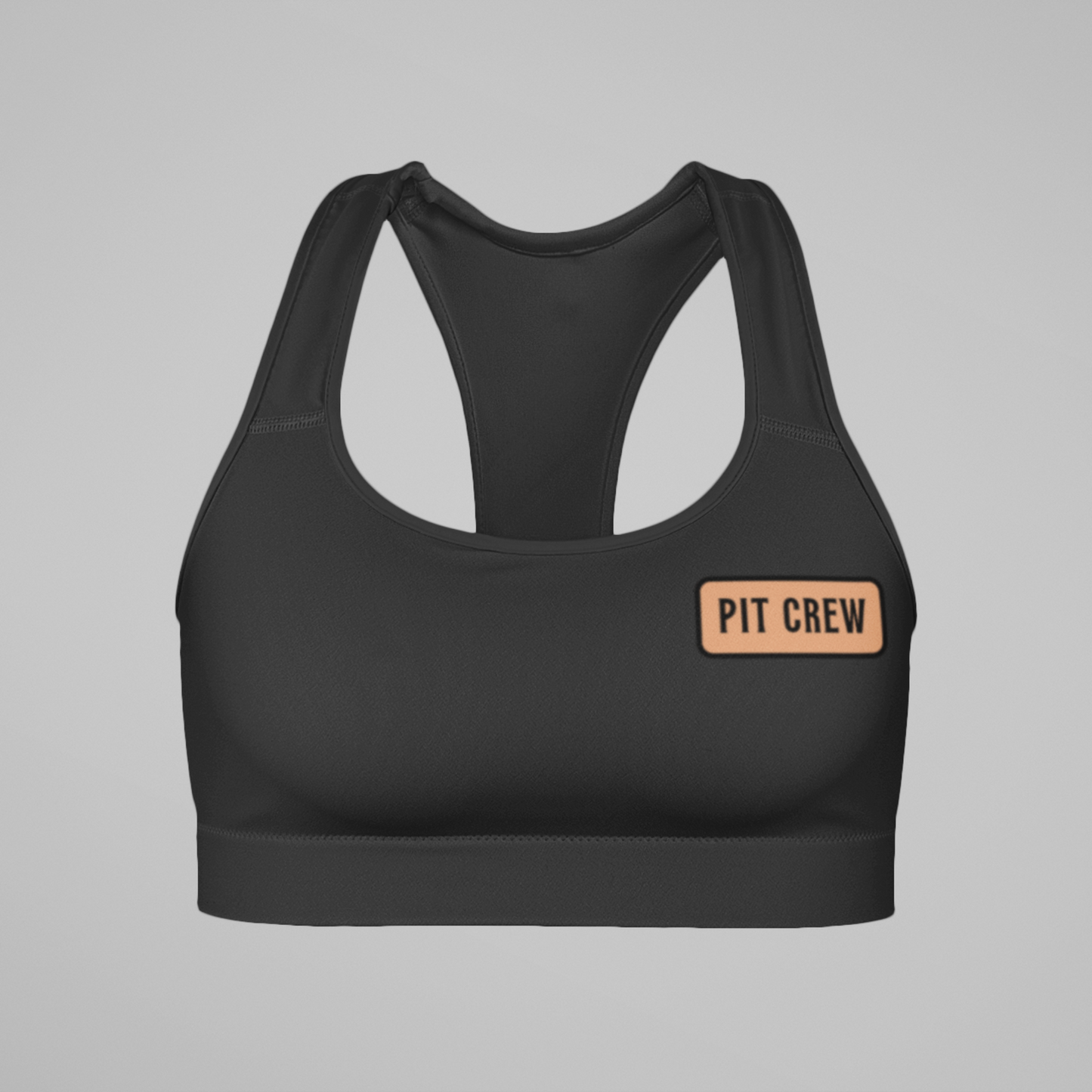 Black sports bra with 'PIT CREW' patch on a gray background