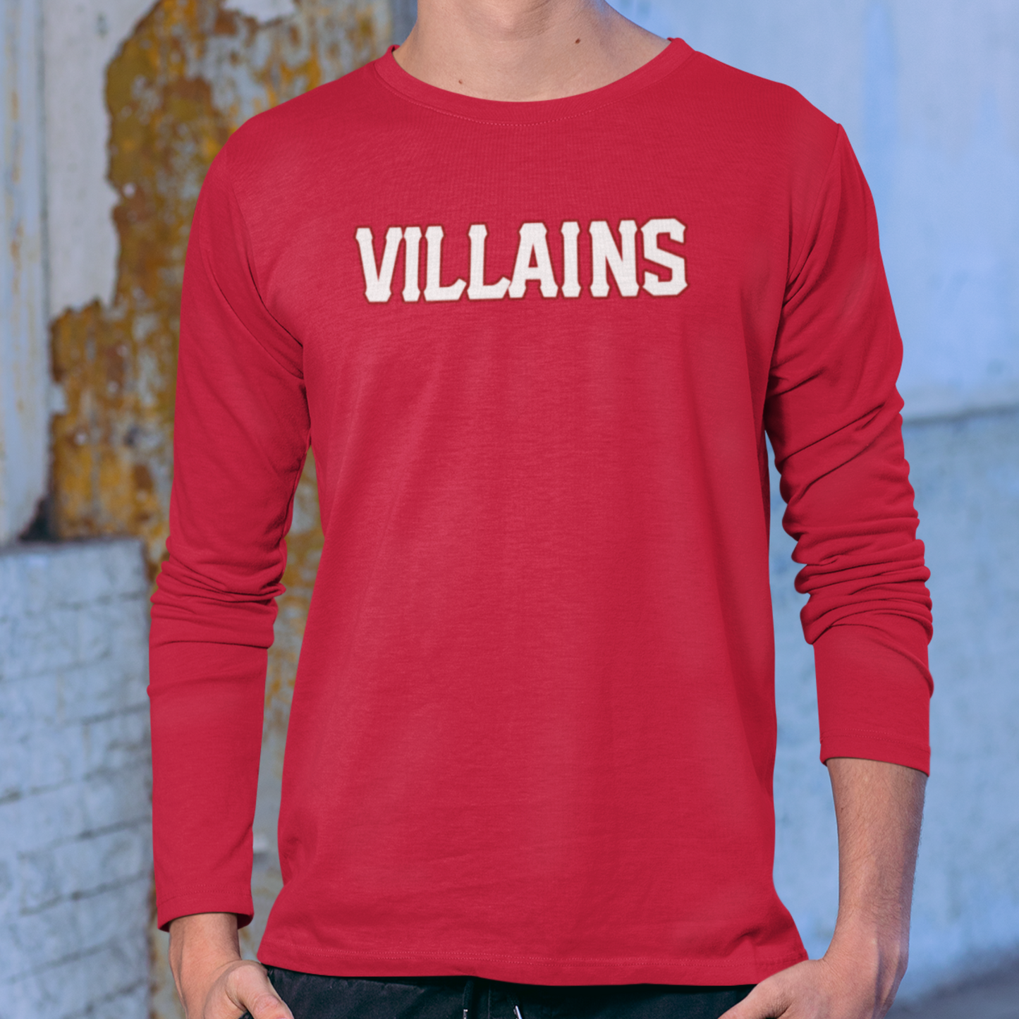 Red long-sleeve shirt with 'VILLAINS' text worn by a person, against a blurred background.