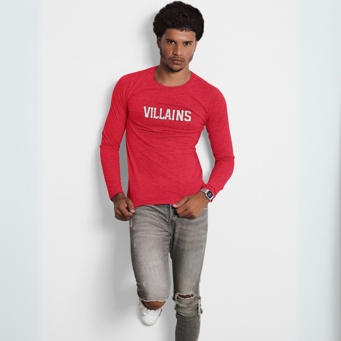 Man wearing a red long-sleeve shirt with 'VILLAINS' text and ripped jeans on a white background