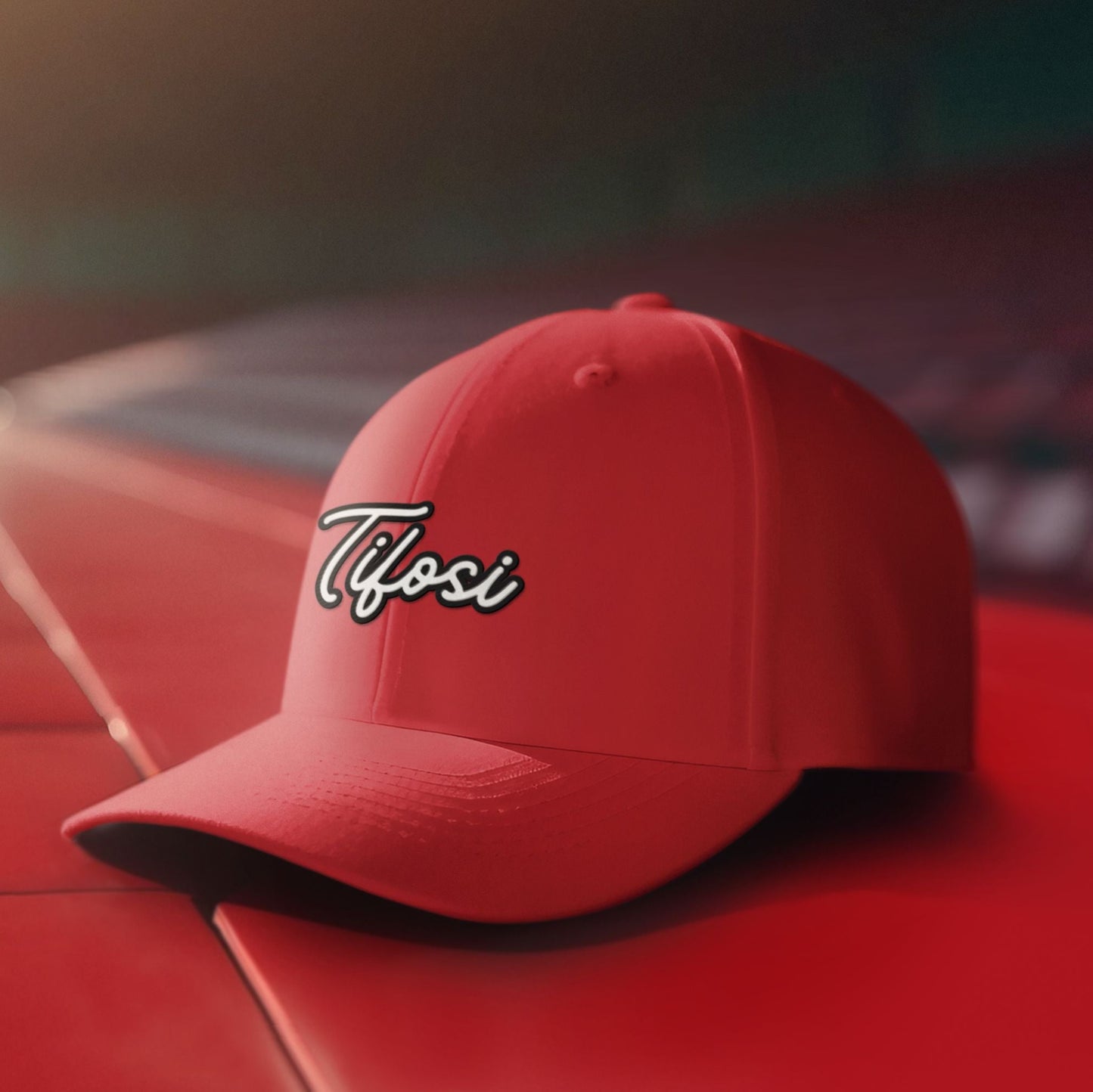 Red cap with 'Tifosi' logo on a red surface with blurred stadium background