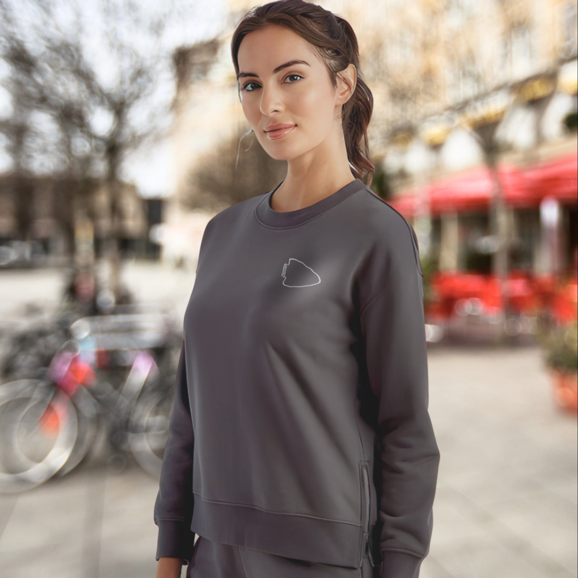Woman wearing a dark gray sweatshirt with a logo in an urban setting