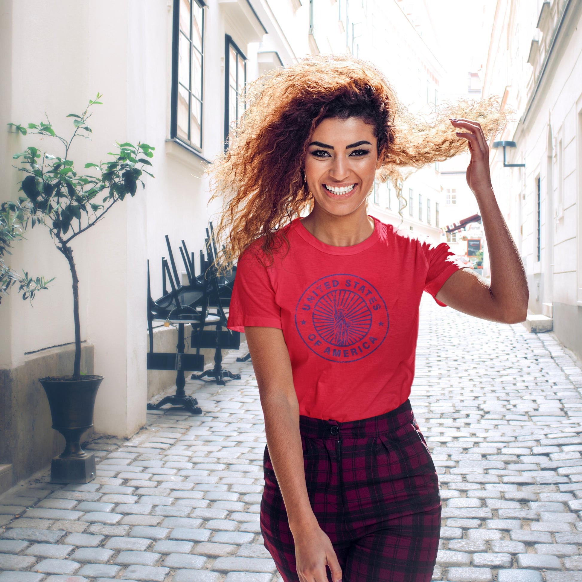 Woman in a red USA t-shirt with a graphic design, standing in an outdoor setting.