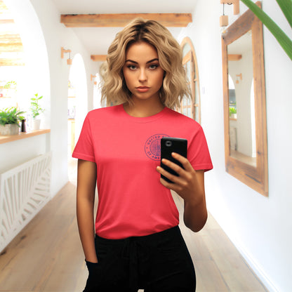Woman wearing a red t-shirt with a logo, holding a phone in a bright indoor setting.