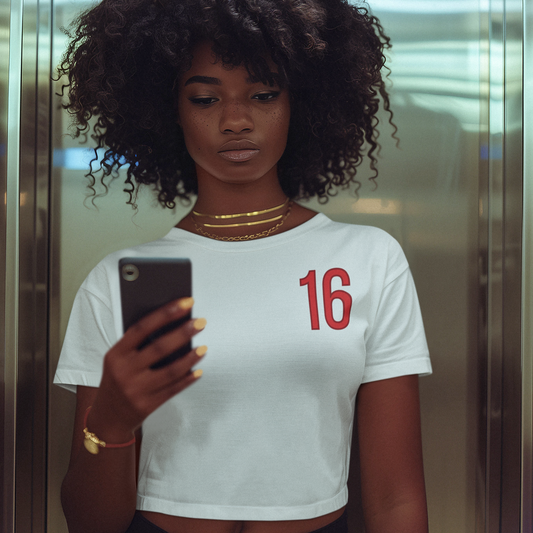 Person taking a mirror selfie wearing a white t-shirt with the number 16 in an elevator.