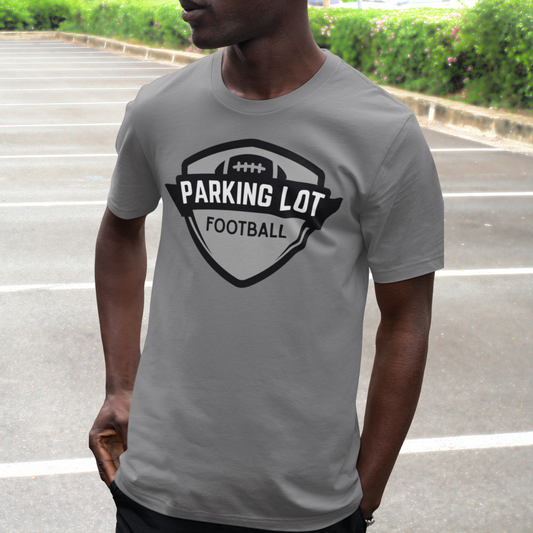 Person wearing a gray t-shirt with 'Parking Lot Football' design outdoors.