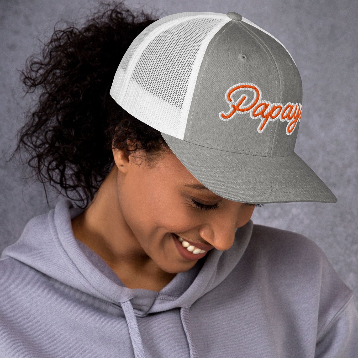 Model wearing a gray and white cap with 'Papaya' branding against a gray background