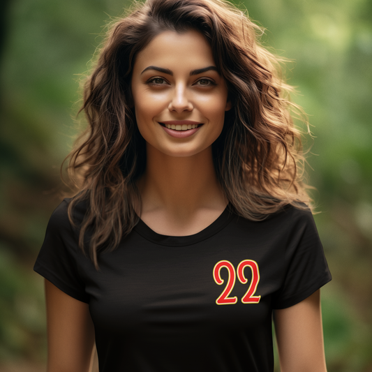 Woman wearing a black t-shirt with the number 22 in orange, standing outdoors with a blurred green background.